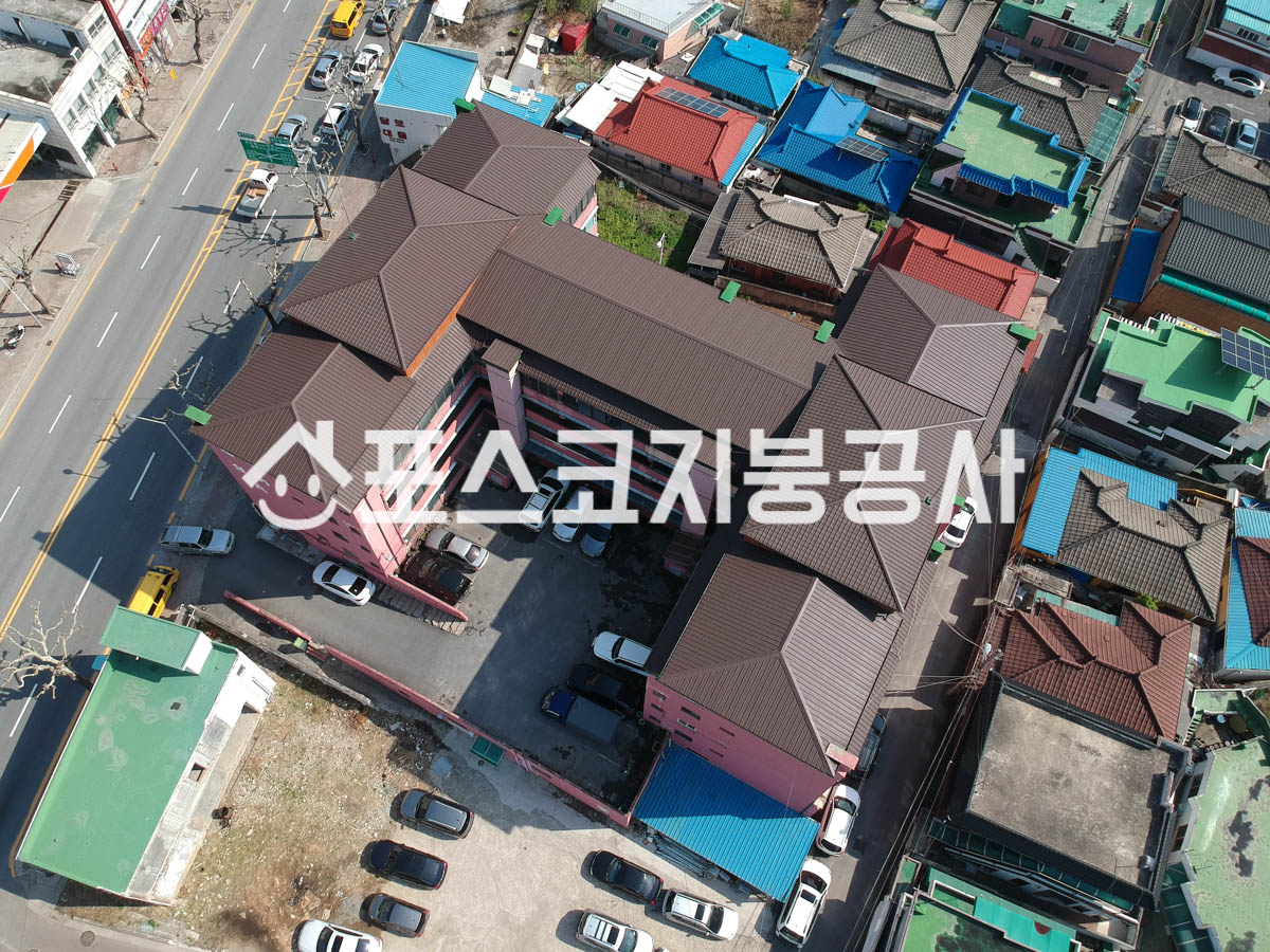 여러 동이 이어진 아파트 슬라브 옥상 위에 갈색 칼라강판 경사지붕을 올린 모습